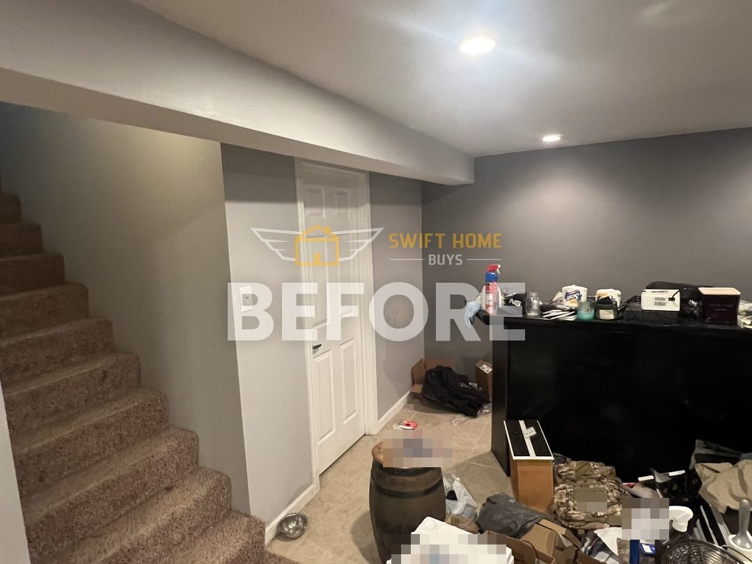Manchester lower level before: gray walls, worn stair carpet and belongings on the floor