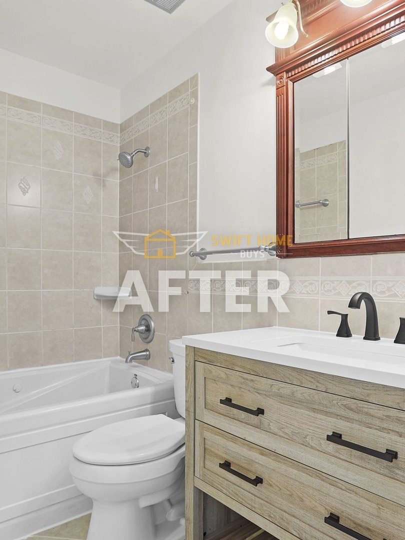 The same Manchester bathroom after: new vanity with a white top, black fixtures and a refreshed tub