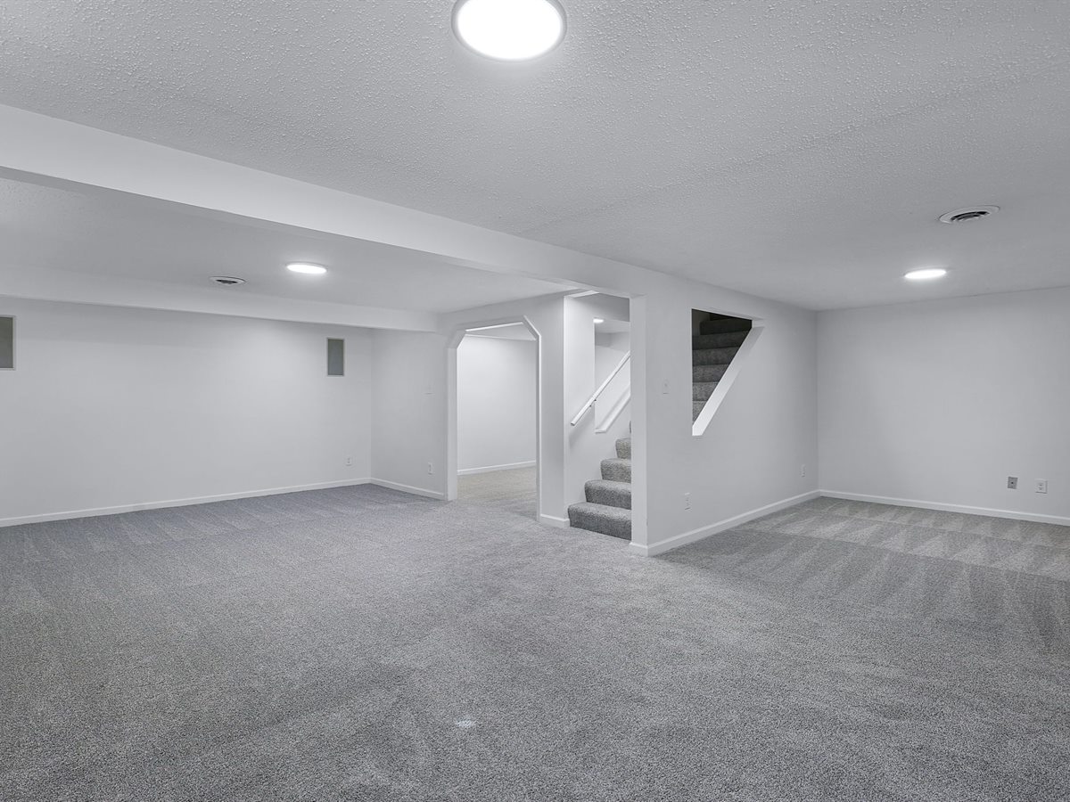 The same Chesterfield basement after: new gray carpet, fresh white paint and new lighting