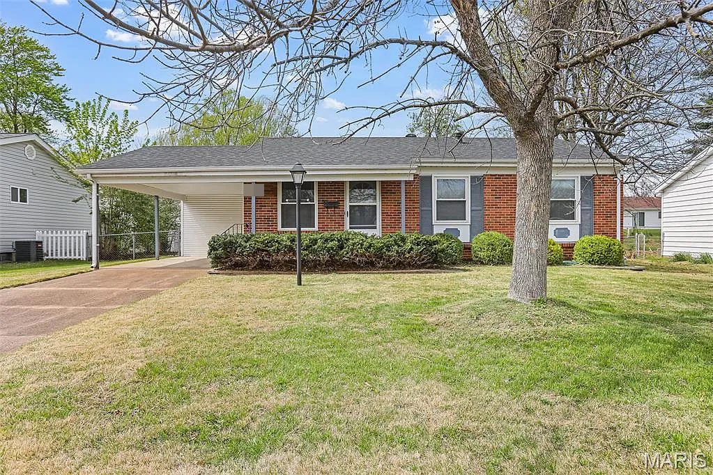 The same Hazelwood brick ranch after, with a dark gray roof, trimmed shrubs and a green lawn