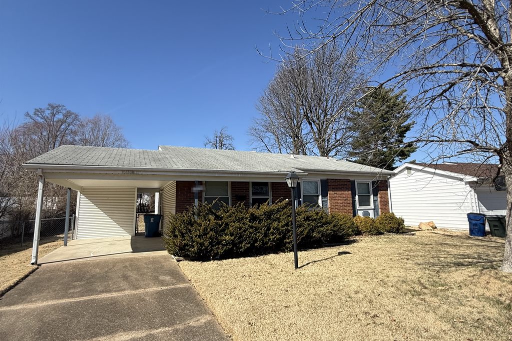 Hazelwood brick ranch before: weathered gray roof, overgrown shrubs and a dormant winter lawn