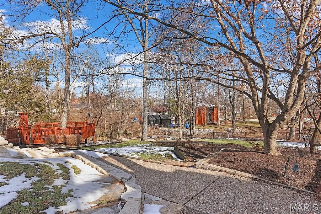 Wooded backyard of the Kirkwood house with a stone walkway, a deck and mature trees