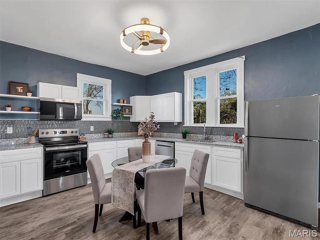 The same Lemay kitchen after renovation: white shaker cabinets, granite counters, stainless appliances and new flooring