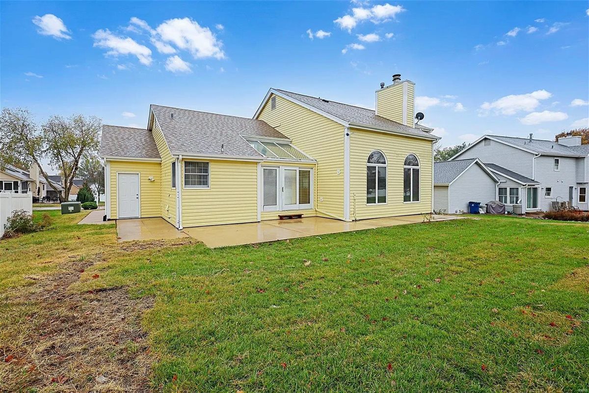 Back of the Oakville house with a large patio, arched windows and an open lawn