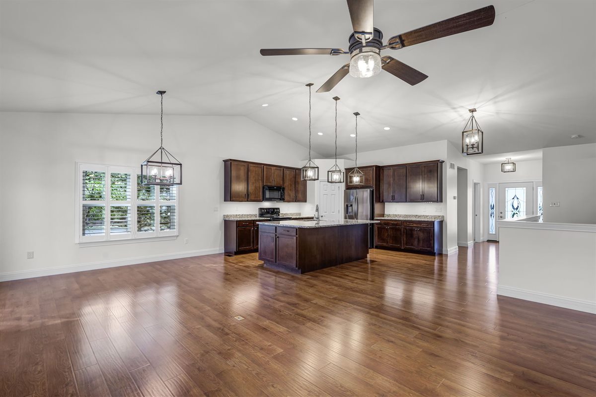 Open kitchen and living area in the St. Peters house after updates, with dark wood cabinets, granite counters and wood-look floors