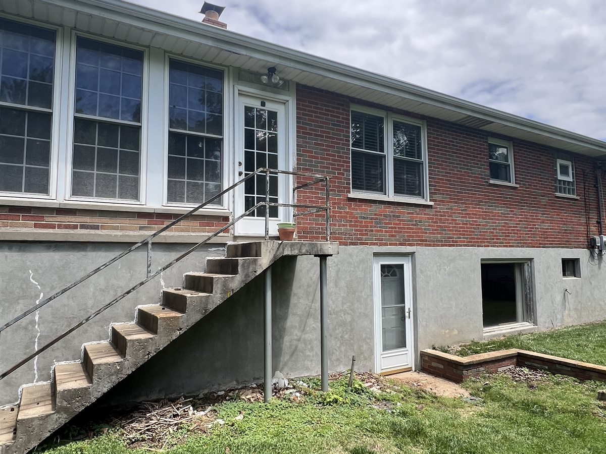 Back of the Sunset Hills ranch before: worn concrete stairs and a patched foundation wall
