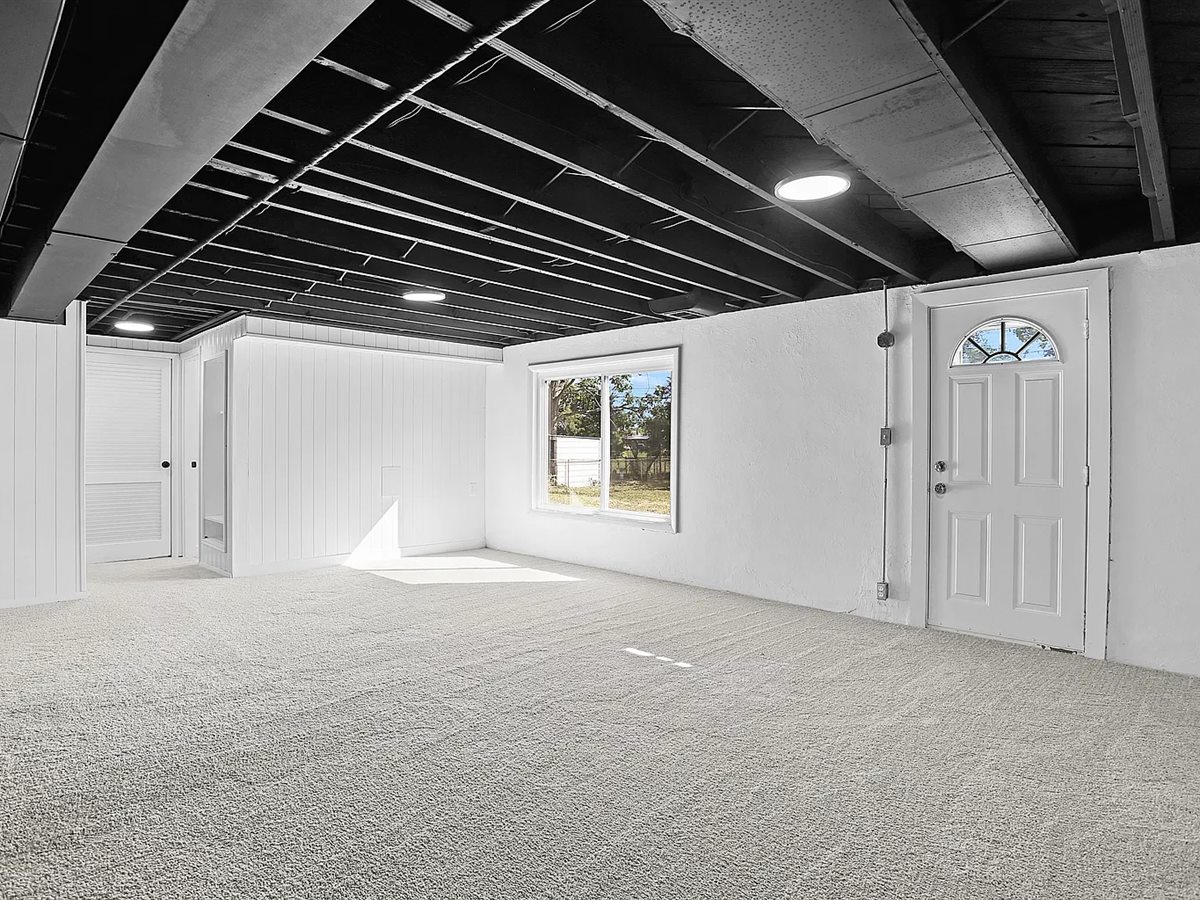 The same Sunset Hills basement after: new carpet, white walls, a painted open ceiling and new lighting