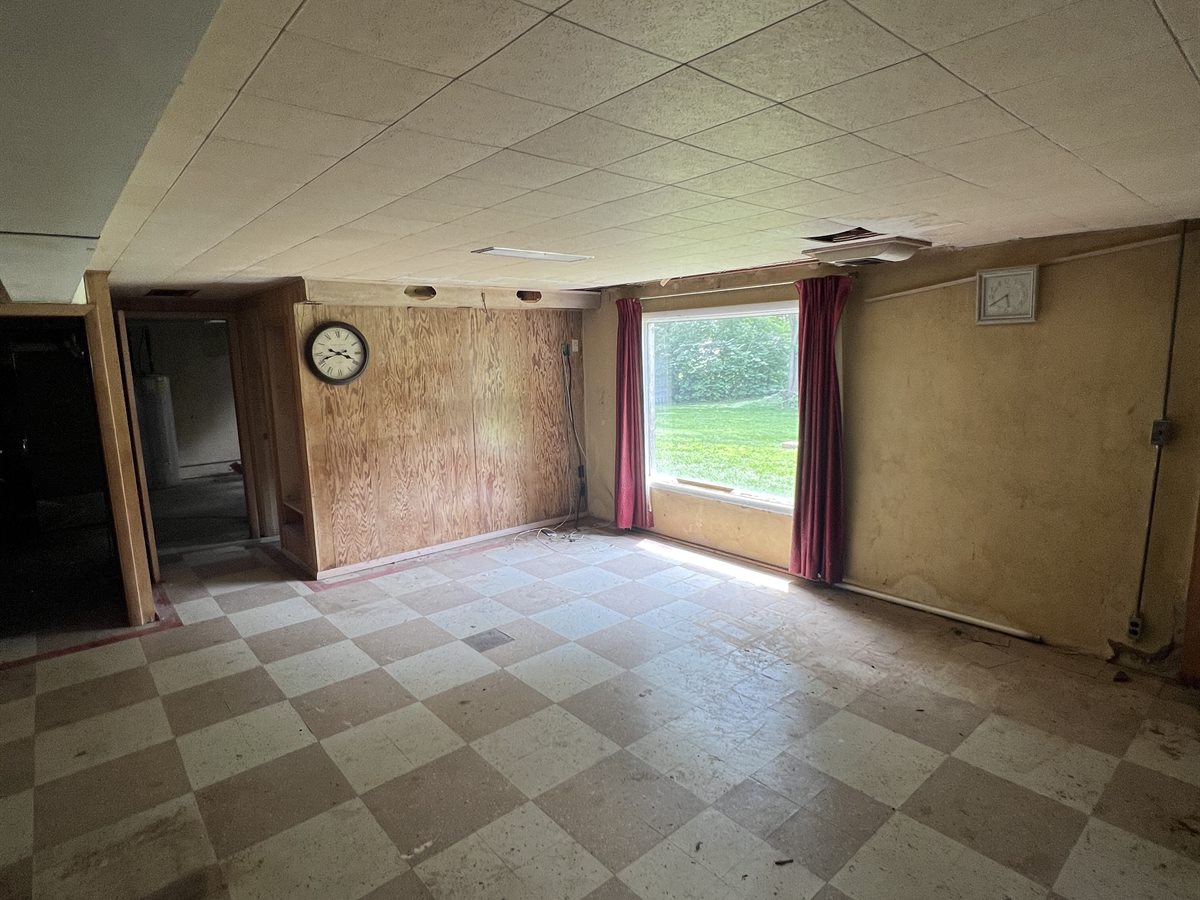 Sunset Hills basement before: checkerboard tile floor, wood paneling, a stained drop ceiling and old curtains
