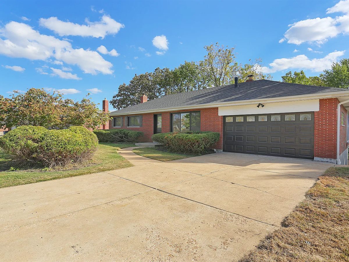 The same Sunset Hills brick ranch after, with a new roof and a dark garage door