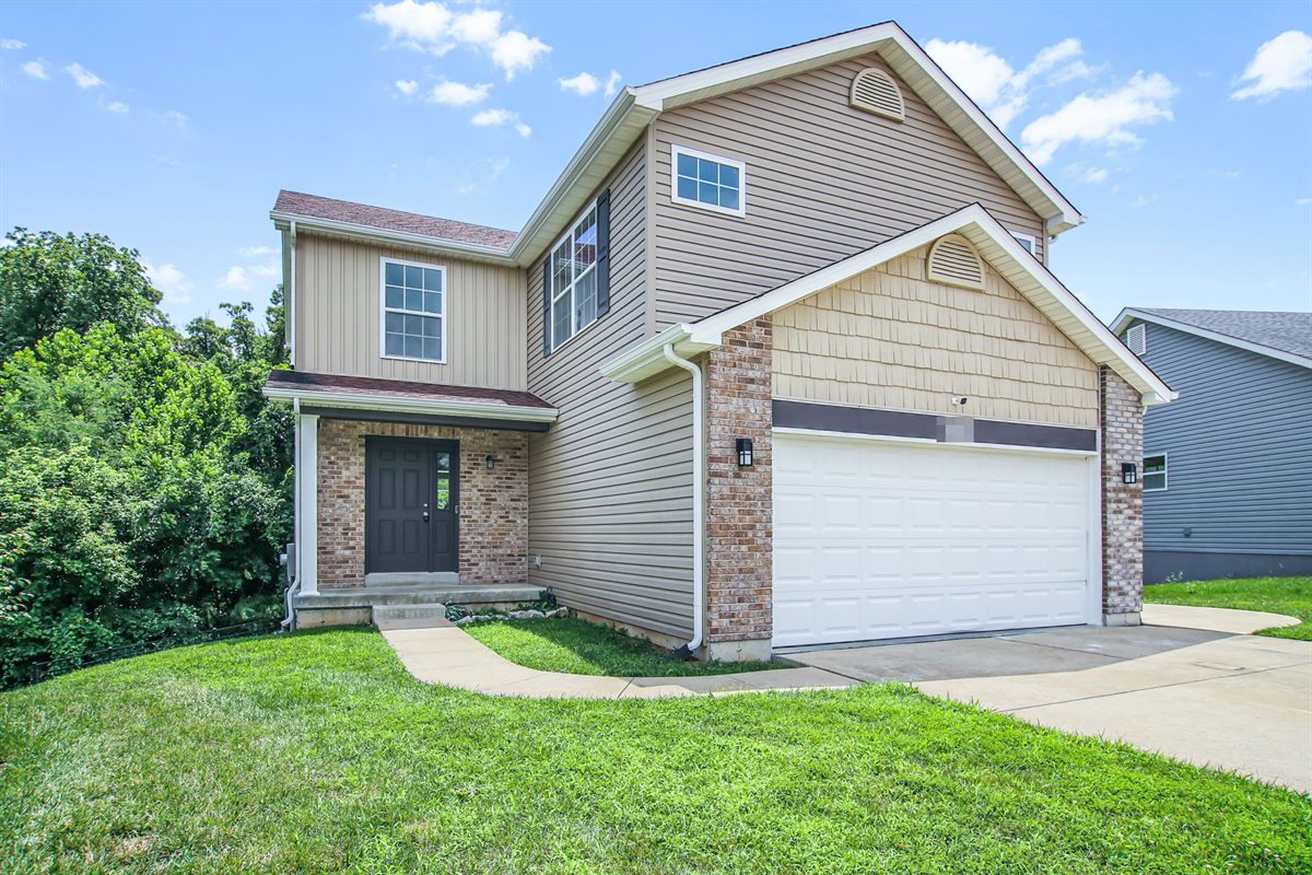 Two-story house with a two-car garage in Wentzville, MO, after Swift Home Buys bought it and replaced the flooring